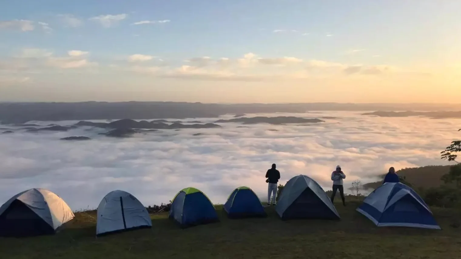 Turistas acampados na Serra do Manecão em Miracatu com nuvens e montanhas no horizonte.