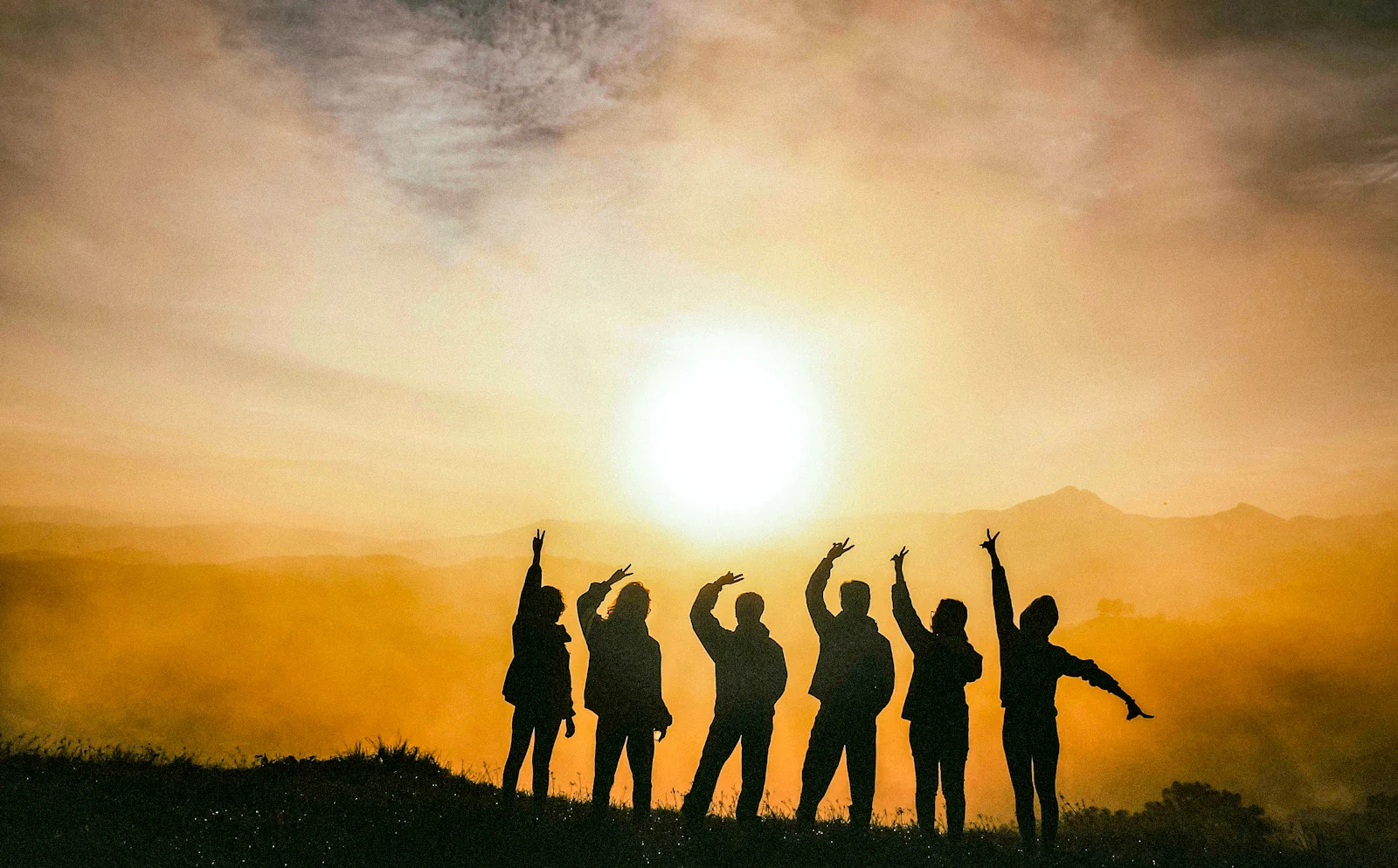 Grupo de turistas assistindo o nascer do sol no topo da montanha.